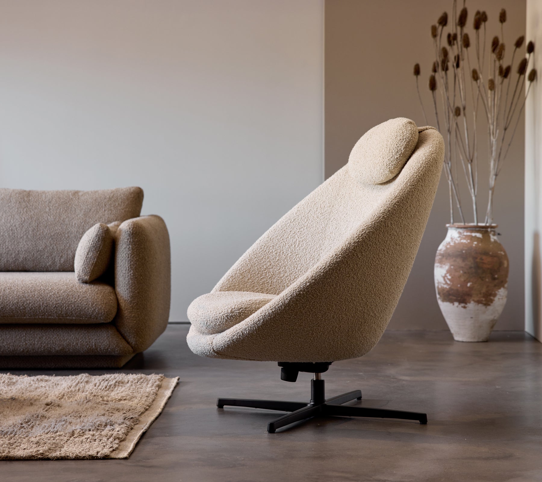Pace stol i taupe stof ved siden af en Bloom 3-personers sofa, suppleret af en dekorativ vase og subtil gulvetekstur.