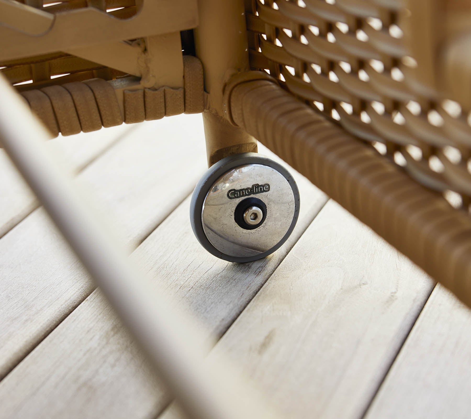 En nærbillede af hjulet på en liggestol, der viser sit design og tekstur mod en træoverflade.