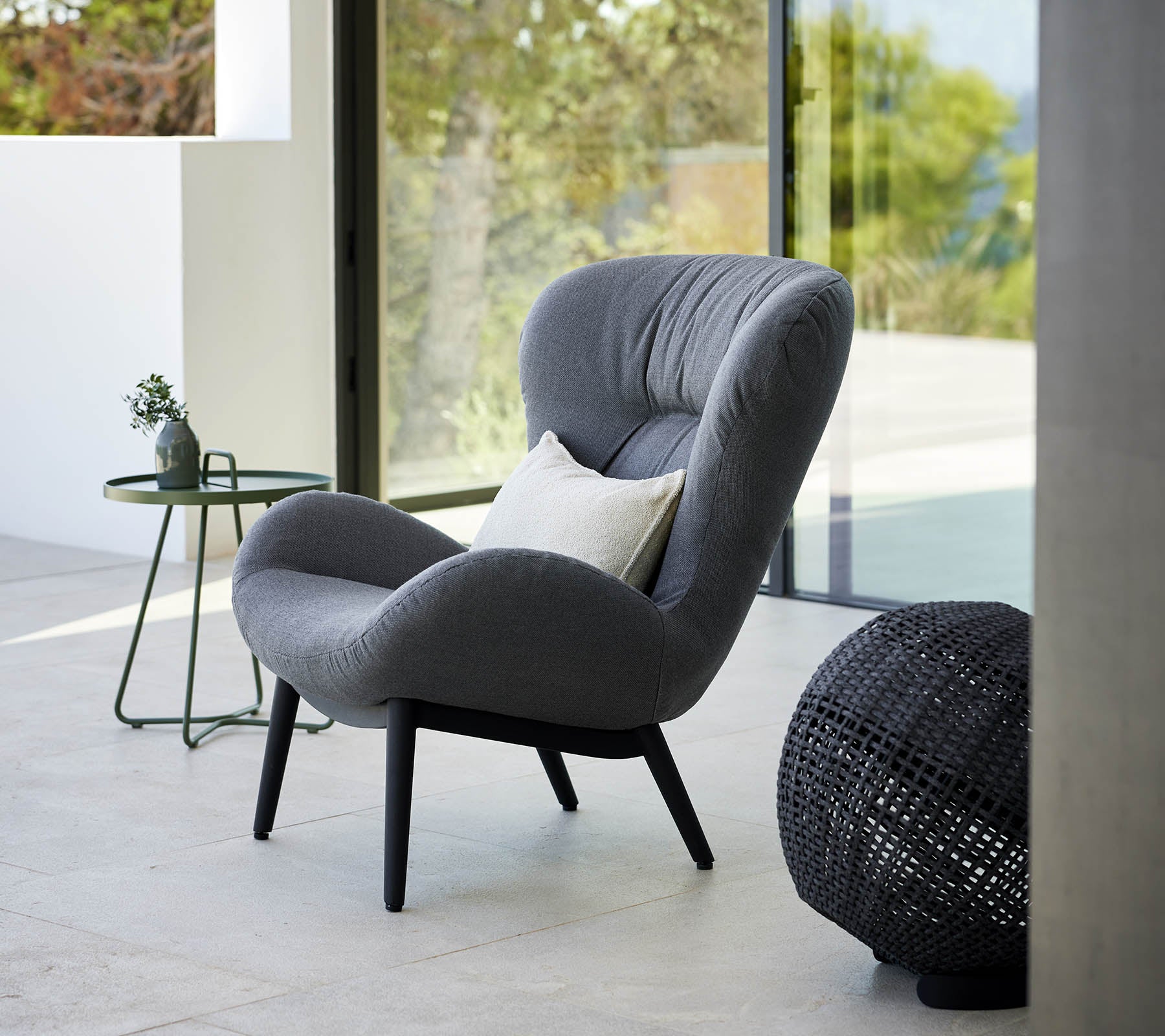 en fredfyldt lounge stol med et moderne design, der har blødt polstring og elegante ben, ledsaget af et lille sidebord og dekorative accenter.