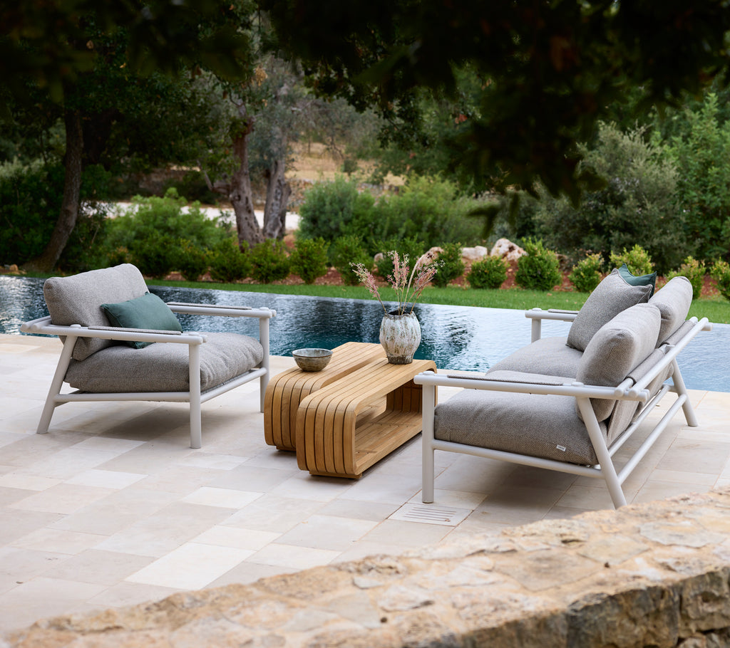 Moderne loungeområde med hvide stole med grå puder og et trækaffebord.