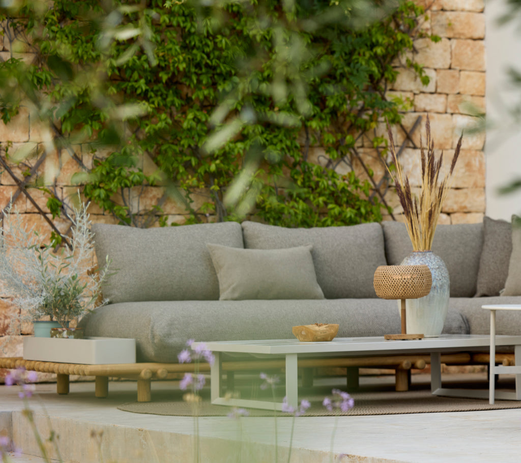 Moderne grå sofa med et træbord i et stilfuldt udendørs loungeområde.