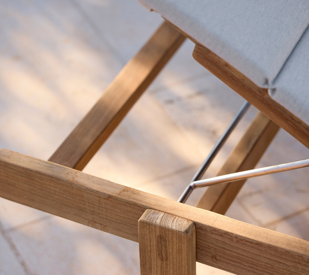 Moderne loungestol med en grå pude og træramme.